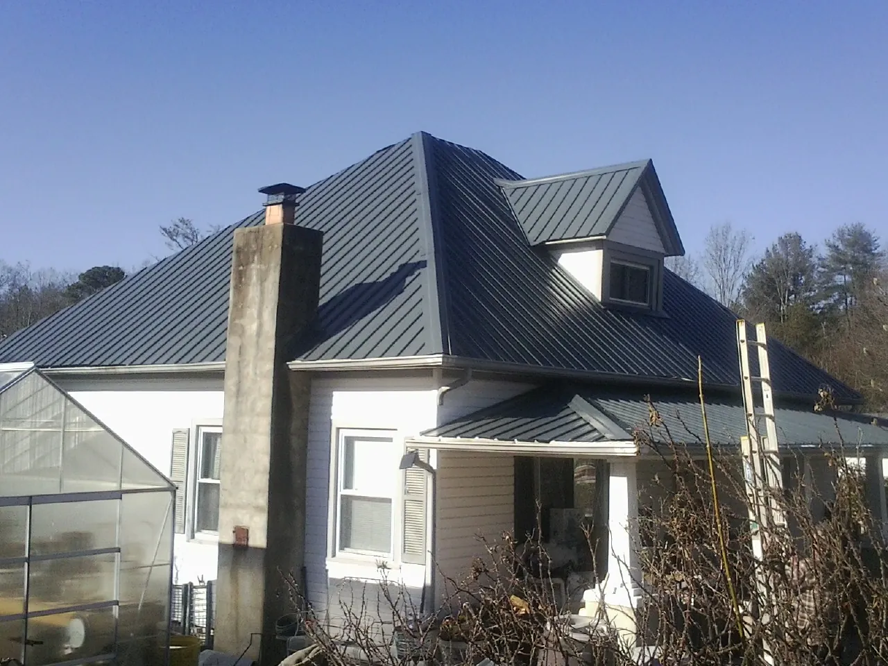 Dark blue standing seam metal roof on a white farmhouse with dormer — Slate & Tile Roof Repair by Roofing Brothers in North Hills