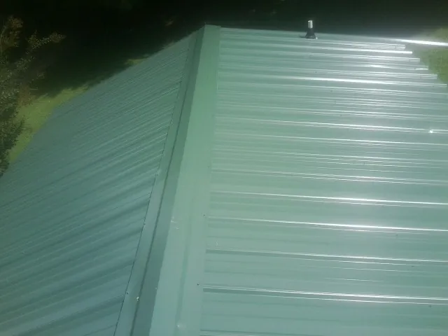 New green metal panels meeting at the ridge of a roof — Flat Roof Repair work by our crew in North Hills