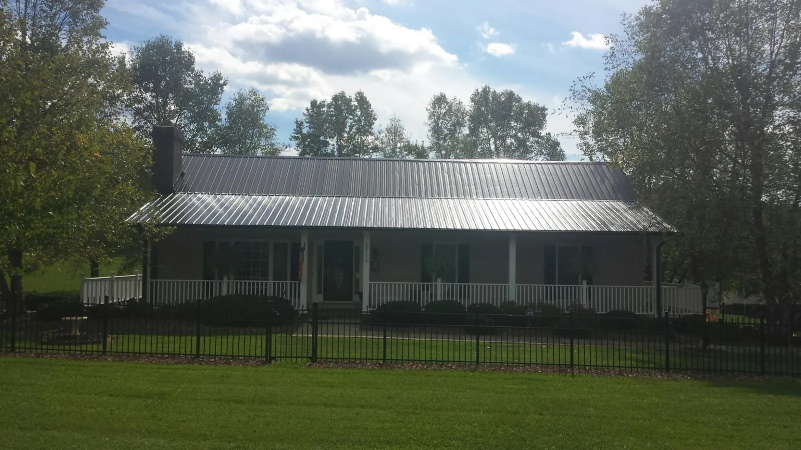 Gray metal roof on a brick ranch with a full width front porch — Gutter Guard Installation work by our crew in North Hills