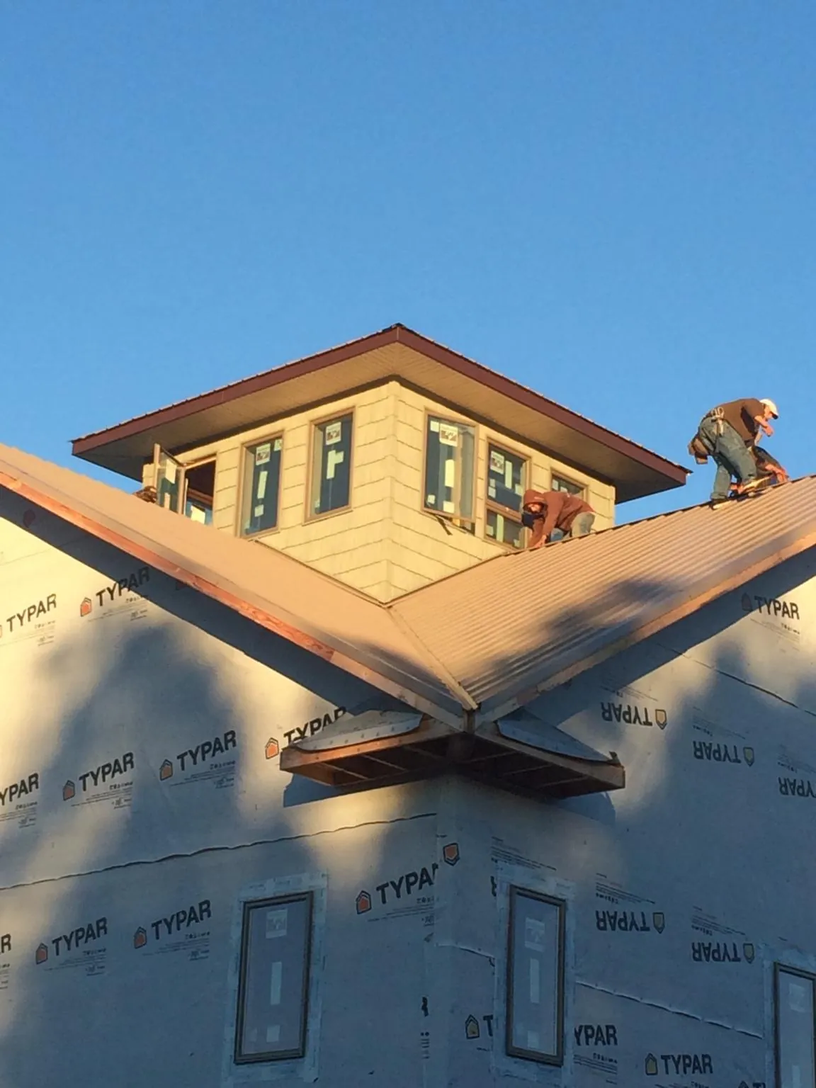 Roofers working around a rooftop cupola on a new metal roof at sunset — Roof Waterproofing in North Hills by Roofing Brothers